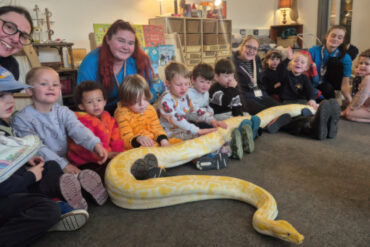 Photo of staff and pupils at Nursery school with giant snake