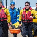 RNLI crew carry a dummy along the seafront