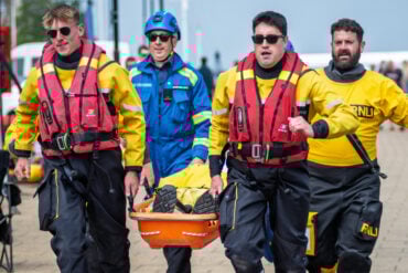 RNLI crew carry a dummy along the seafront