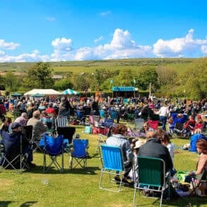 Audience seated in fold up chairs in the field at Wolverton Manor for the Folk and Blues Day