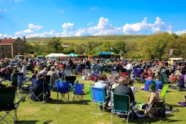 Audience seated in fold up chairs in the field at Wolverton Manor for the Folk and Blues Day