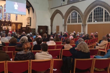 people seated in st catherines church attending the screening of the emergency briefing