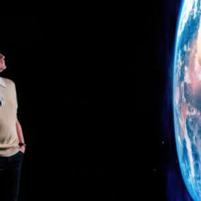 Chris packham looking at a large projection of earth from space