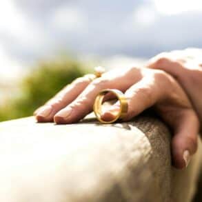 Person holding a wedding ring on a fence