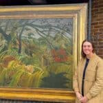 The National Gallery’s Head of Exhibitions, Alex Kavanagh, standing in front of Surprised! by Henri Rousseau at Newport Bus Station