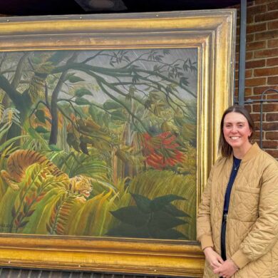 The National Gallery’s Head of Exhibitions, Alex Kavanagh, standing in front of Surprised! by Henri Rousseau at Newport Bus Station