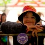 child at three rivers music festival smiling into the camera