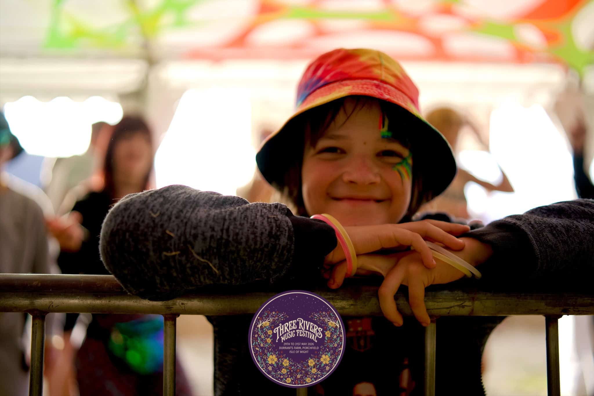 child at three rivers music festival smiling into the camera