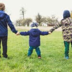 three children out on a walk in country holding hands