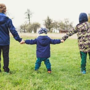 three children out on a walk in country holding hands