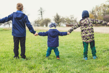 three children out on a walk in country holding hands