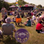 Photo from three rivers music festival showing people sitting in front of stage
