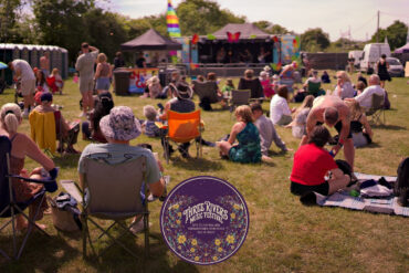 Photo from three rivers music festival showing people sitting in front of stage