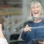Photo taken from outside through the glass of two women talking at the Ronson Reunited event
