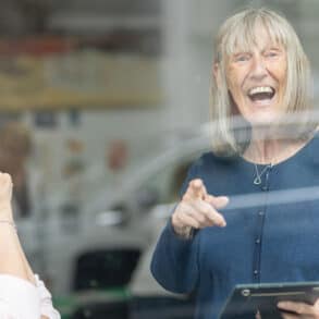 Photo taken from outside through the glass of two women talking at the Ronson Reunited event