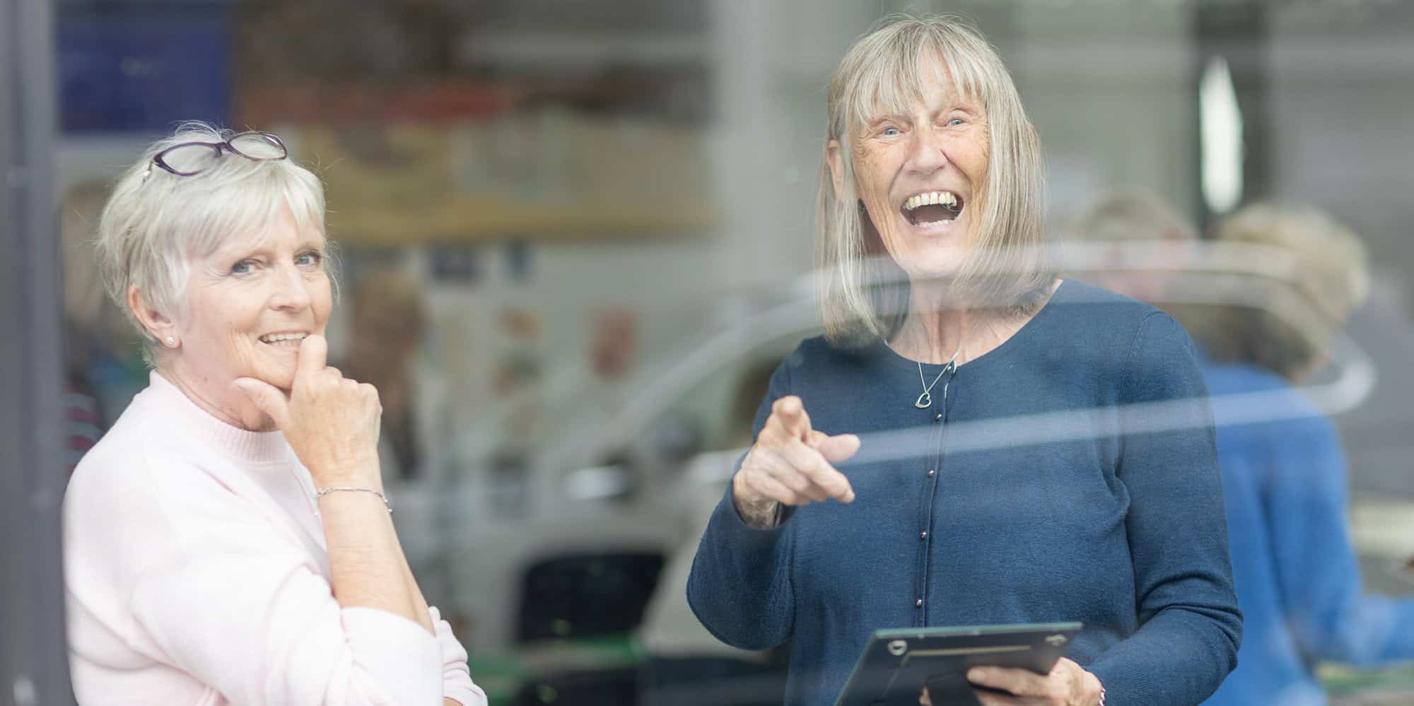 Photo taken from outside through the glass of two women talking at the Ronson Reunited event