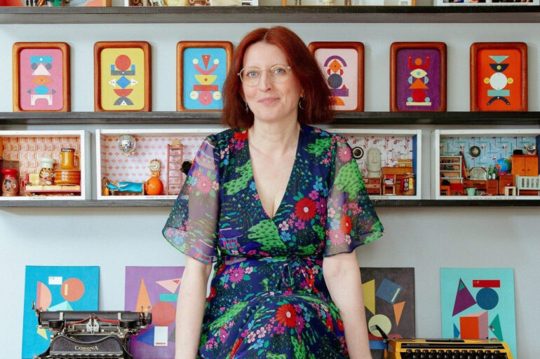Fran Heath sitting on her desk surrounded by her dire-ramas and vintage typewriters
