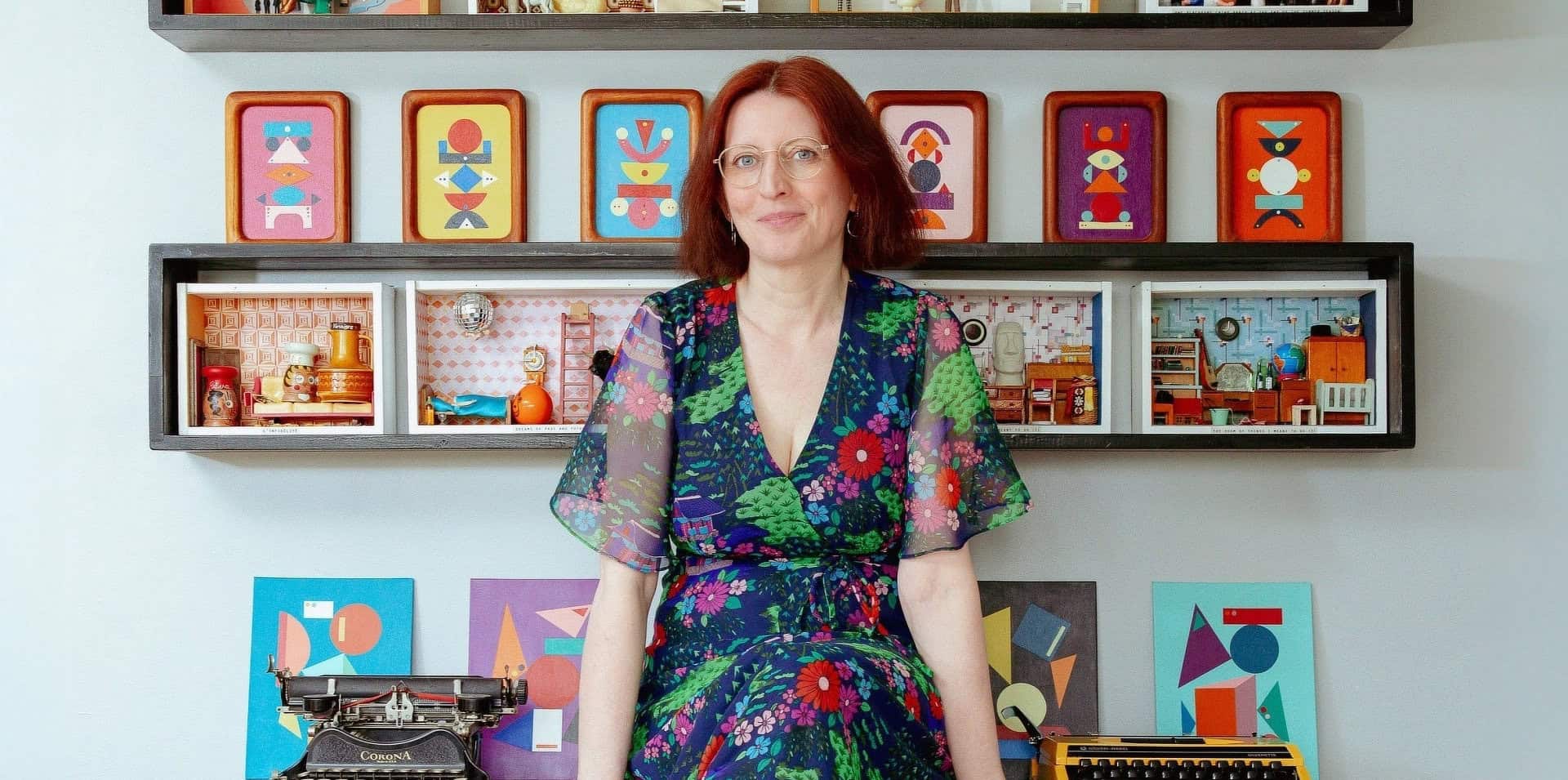 Fran Heath sitting on her desk surrounded by her dire-ramas and vintage typewriters