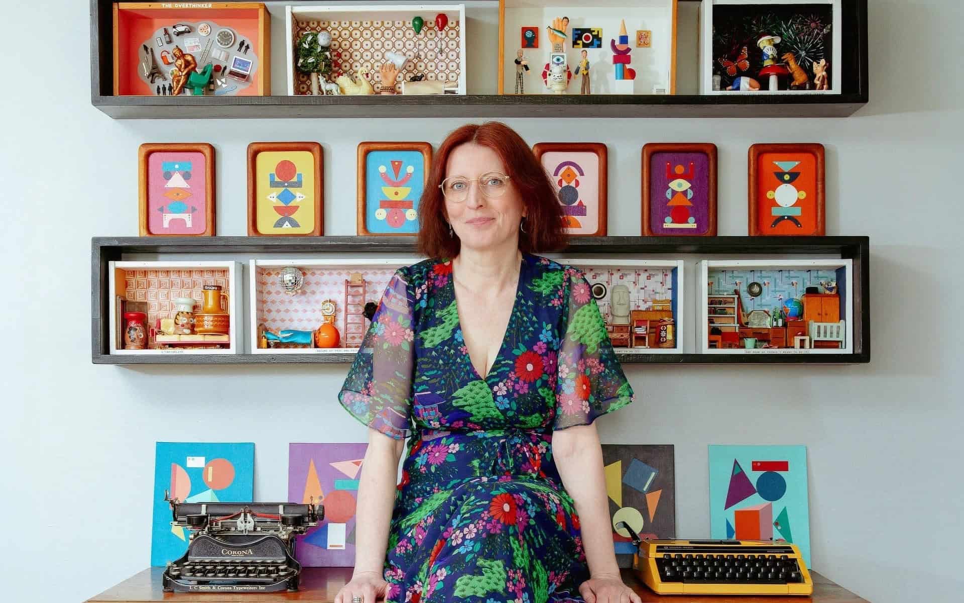 Fran Heath sitting on her desk surrounded by her dire-ramas and vintage typewriters