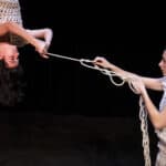 Two women performing on stage with rope entwining them