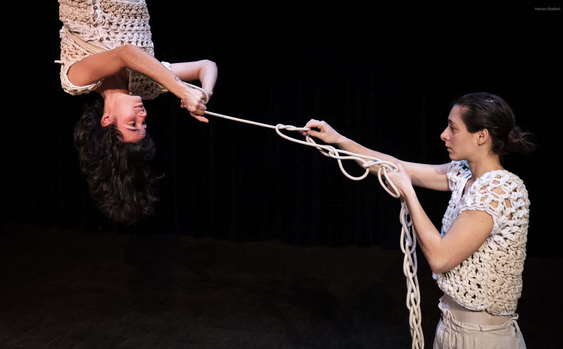 Two women performing on stage with rope entwining them