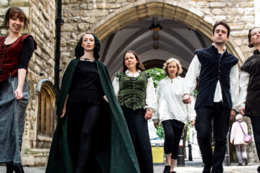 The cast of Impromptu Shakespeare walking through old courtyard