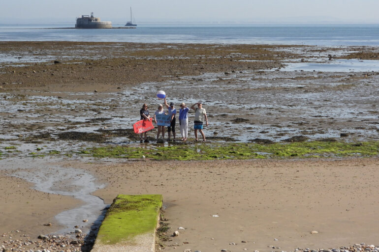 Distance shot of No Poo at the Point campaigners standing where the pipe will come out