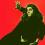 Performer dressed all in black acting as though he is falling against a red background