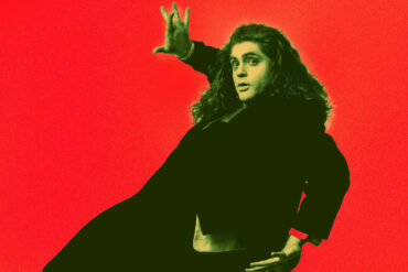 Performer dressed all in black acting as though he is falling against a red background