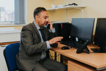 NHS GP sitting at desk on the phone