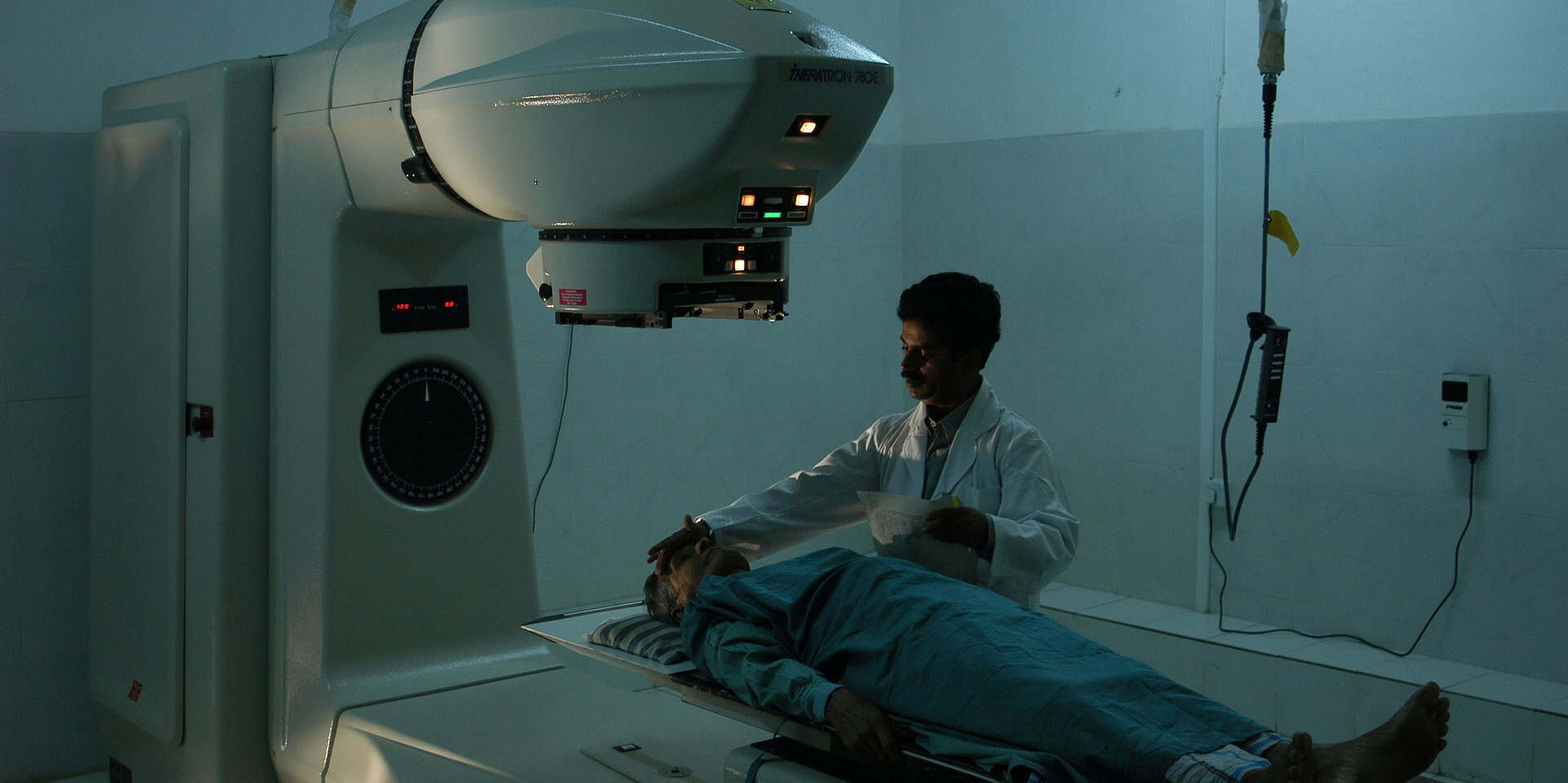 Patient lying on a Radiotherapy machine bed with nurse standing next to them