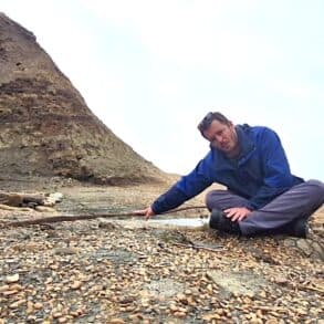 Jack sitting on the beach pointing to some old steel rails