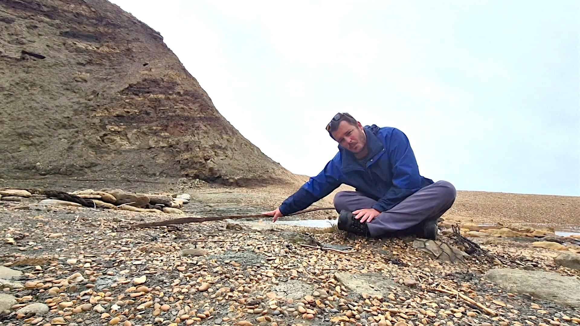 Jack sitting on the beach pointing to some old steel rails