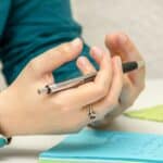 person sitting at a desk with note paper and pen