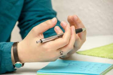 person sitting at a desk with note paper and pen