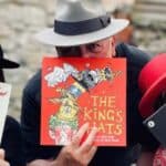 Three people wearing hats and holding hat-related story boks in front of their faces