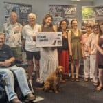 A group of people posing for photo with a giant WightAID cheque
