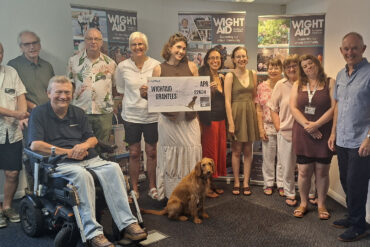 A group of people posing for photo with a giant WightAID cheque