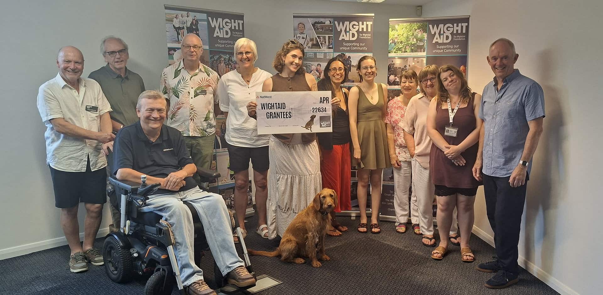 A group of people posing for photo with a giant WightAID cheque