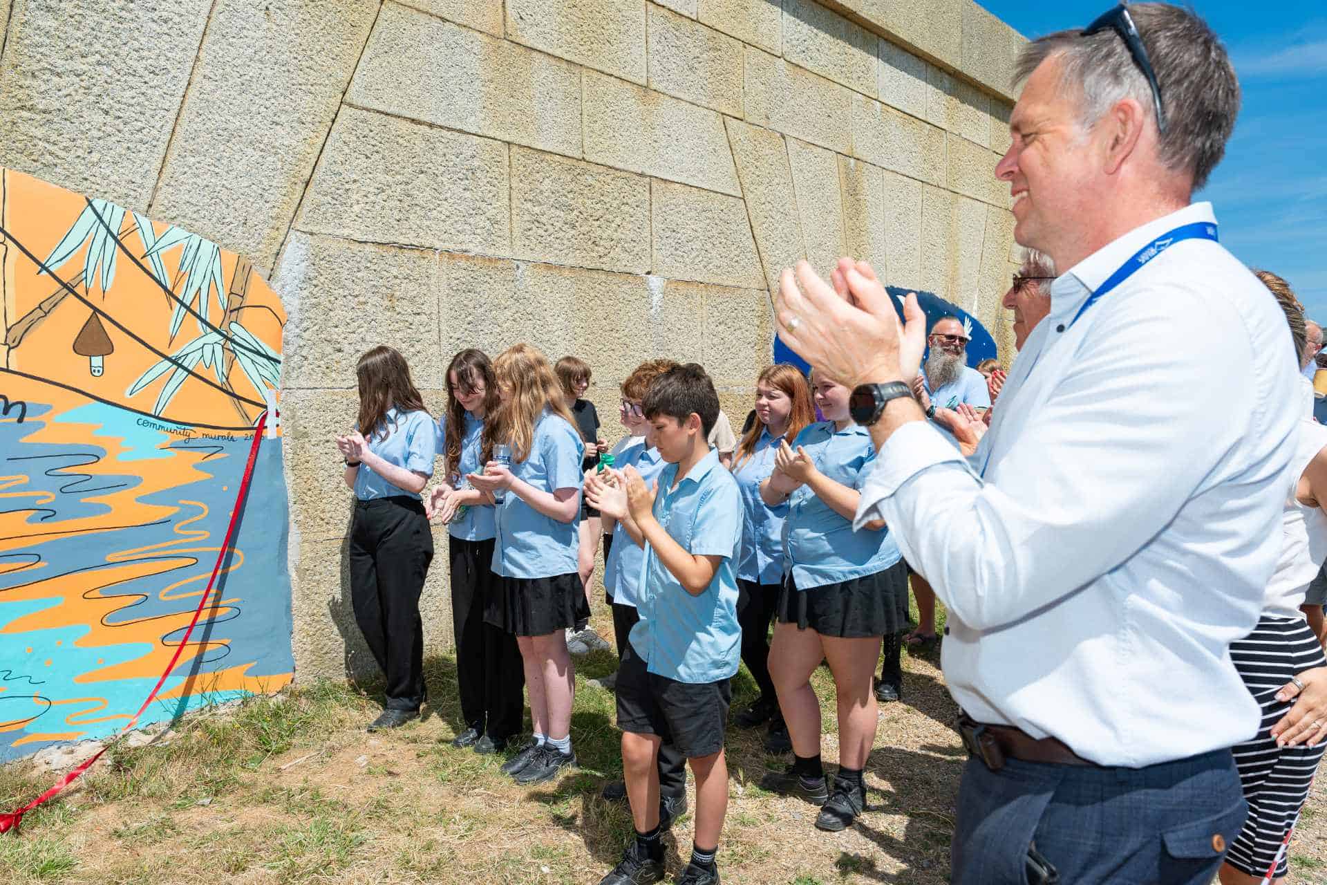 Pupils and dignitories attending the official opening of the murals