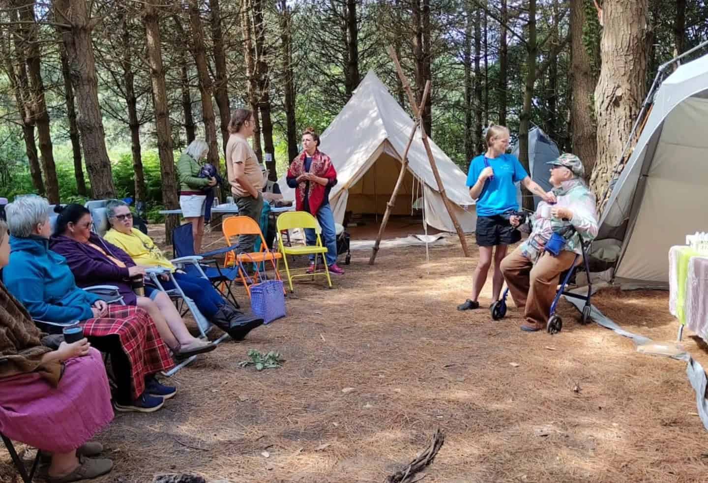 Group of people sitting in a circle in a clearing in the woods