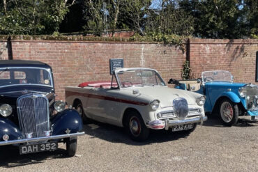 Singer Motor cars from three eras in a car park -