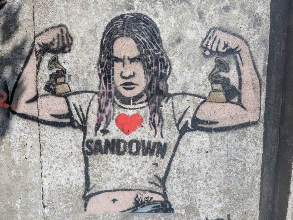 Stencil art on a concrete wall of the Wet Leg singer Rhian Teasdale wearing a I Love Sandown T-shirt