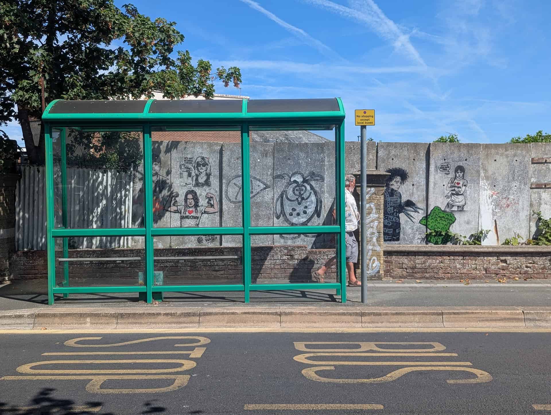 View of graffitied concrete wall by the bus stop