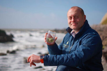 Xavier Baker from Isle of Wight distillery by the sea with a glass of Mermaid Gin and Tonic
