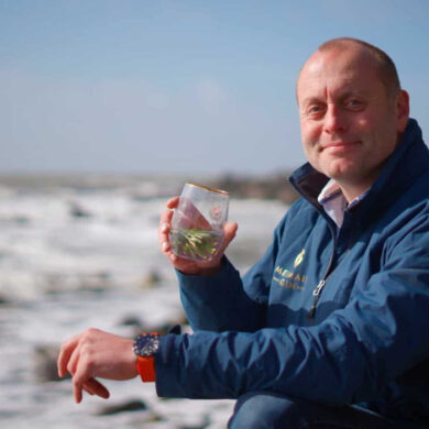 Xavier Baker from Isle of Wight distillery by the sea with a glass of Mermaid Gin and Tonic