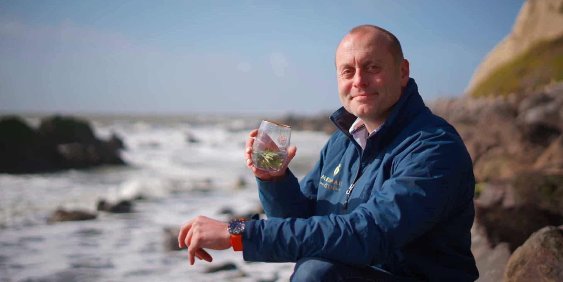 Xavier Baker from Isle of Wight distillery by the sea with a glass of Mermaid Gin and Tonic