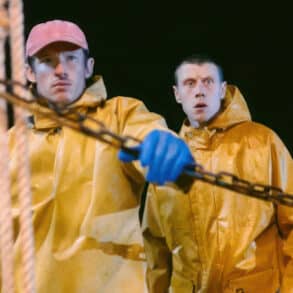 Two fishermen on a boat at night, wearing yellow waterproofs