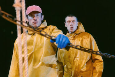Two fishermen on a boat at night, wearing yellow waterproofs
