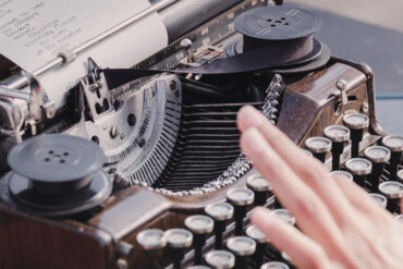 person typing a poem on a traditional typewriter